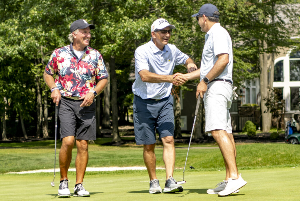 Golfers shaking hands on the green during the Ben Curtis Golf Classic charity golf event supporting local children and families.