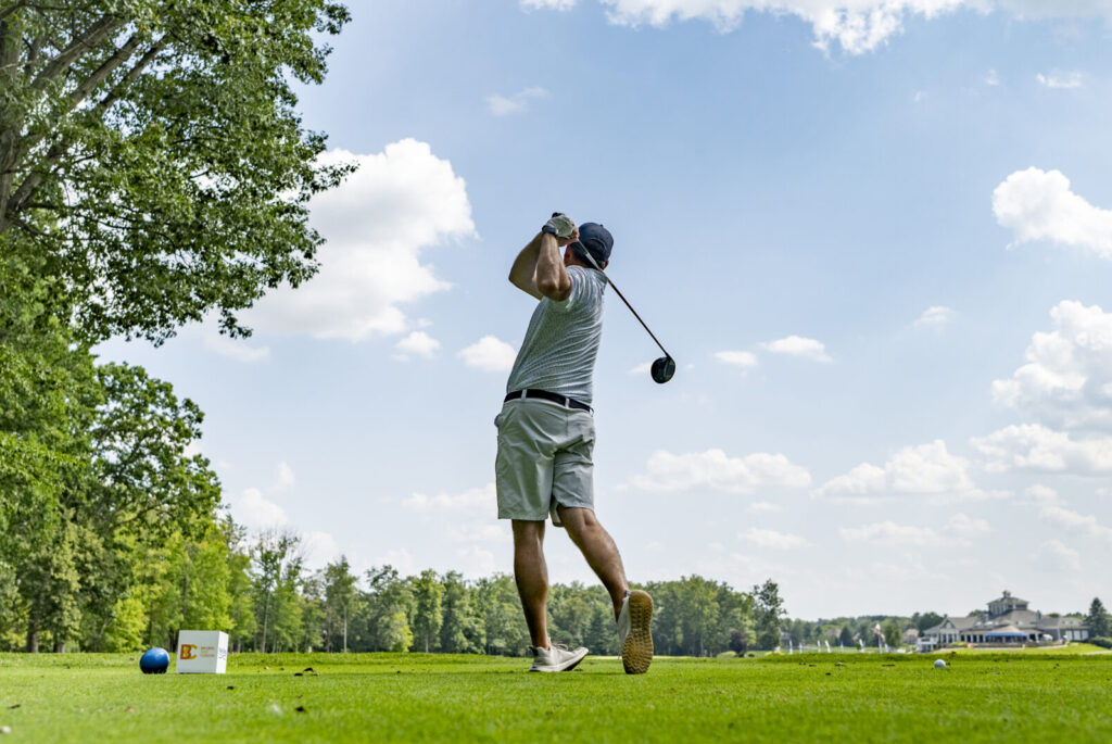 Golfer teeing off on the course during the Ben Curtis Golf Classic charity golf event supporting local children and families.