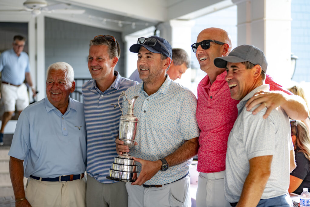 Golf event participants posing together with a trophy at the Ben Curtis Golf Classic charity golf event supporting local children and families.